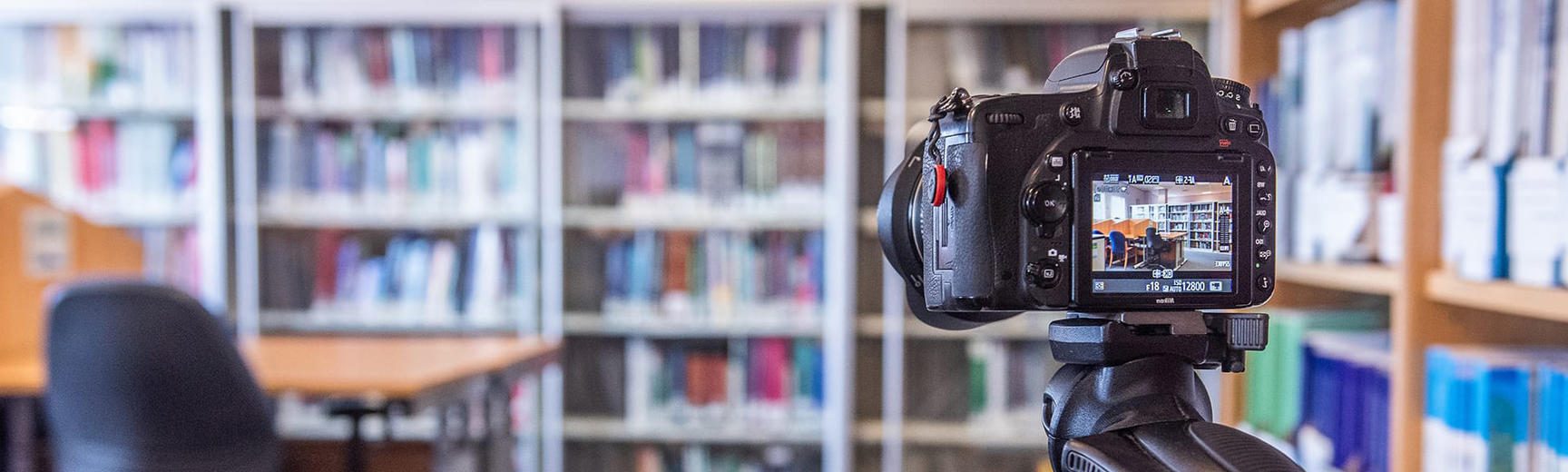 A digital camera positioned in front of a room of bookshelves