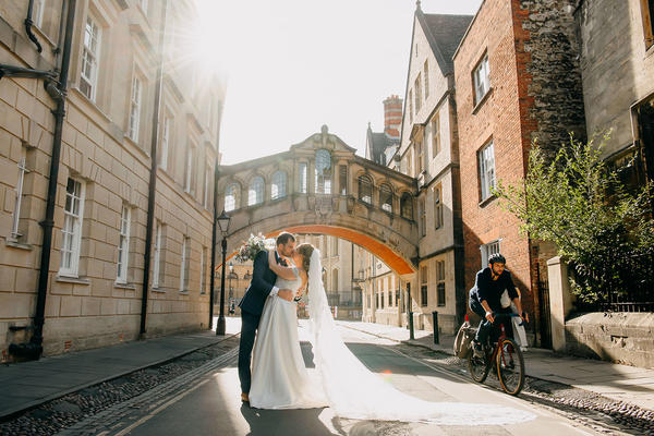 A couple kiss under the Bridge of Sighs as a cyclist rides passed