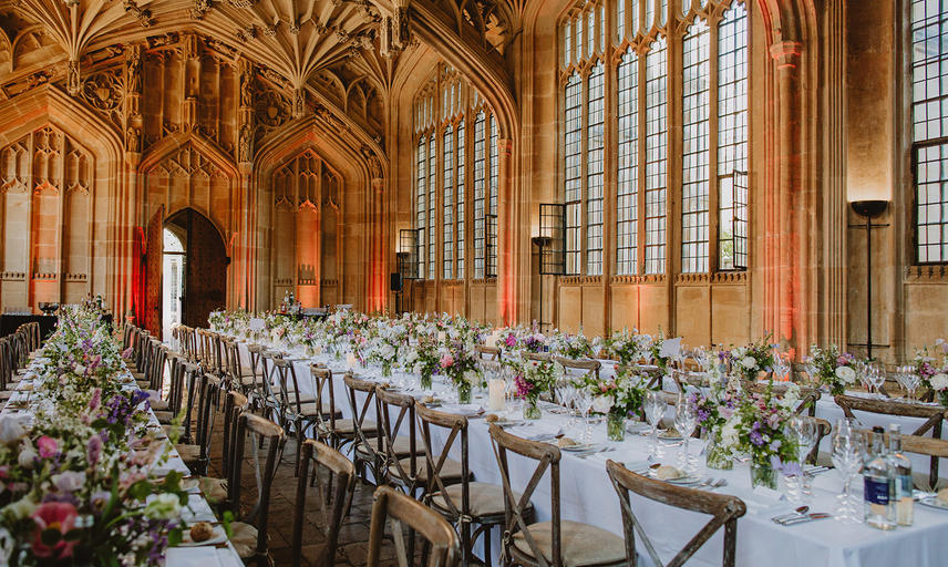 Two long tables laid with a white tablecloth and vases of pastel flowers