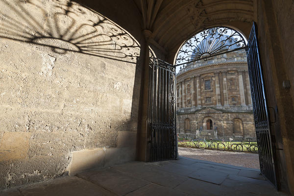 A view through a gateway of the Radcliffe Camera - a large domed building in the centre of a public square