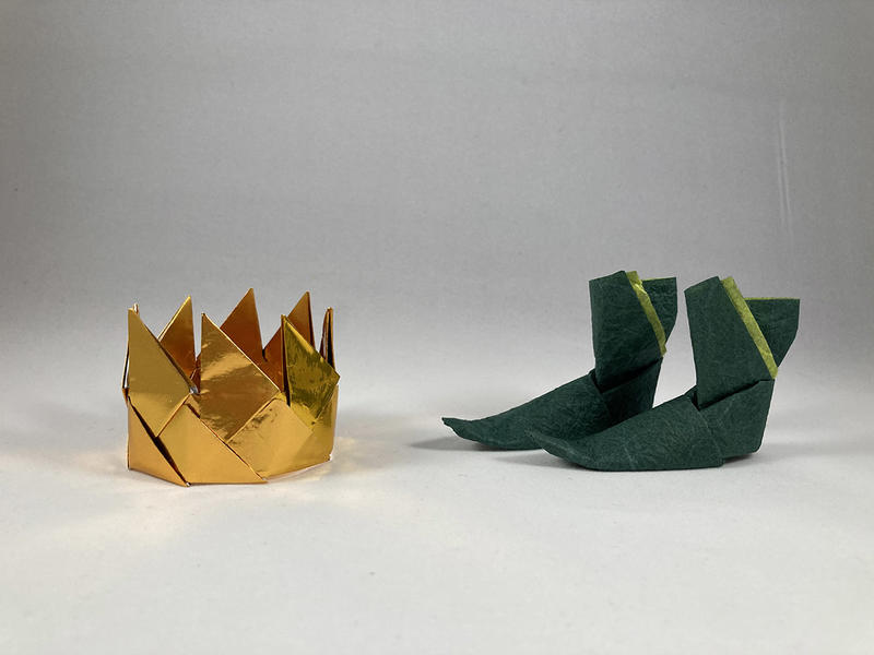 A gold crown to the left and a pair of green boots to the right - both made from paper